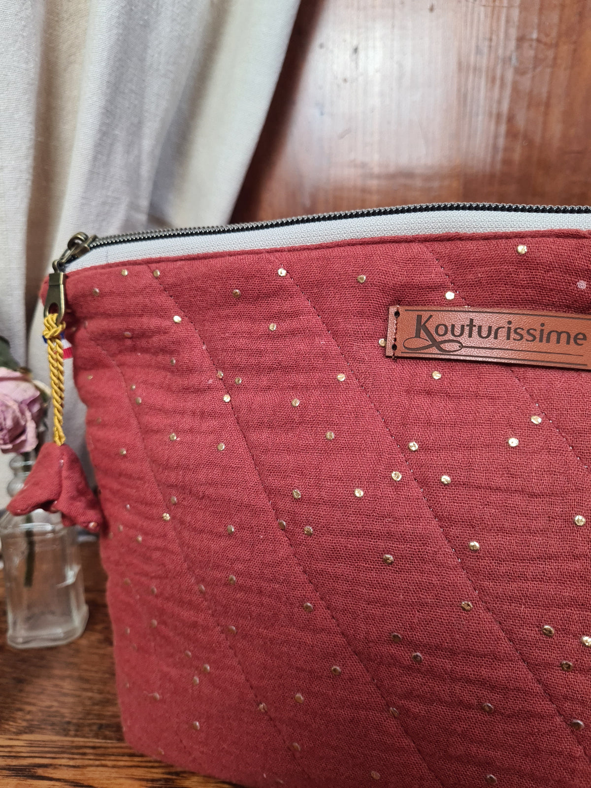 Détail de la fermeture zippée et de l’étiquette Kouturissime sur la trousse terracotta